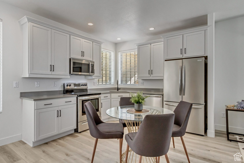 Kitchen with white cabinetry, light hardwood / wood-style floors, appliances with stainless steel finishes, and sink