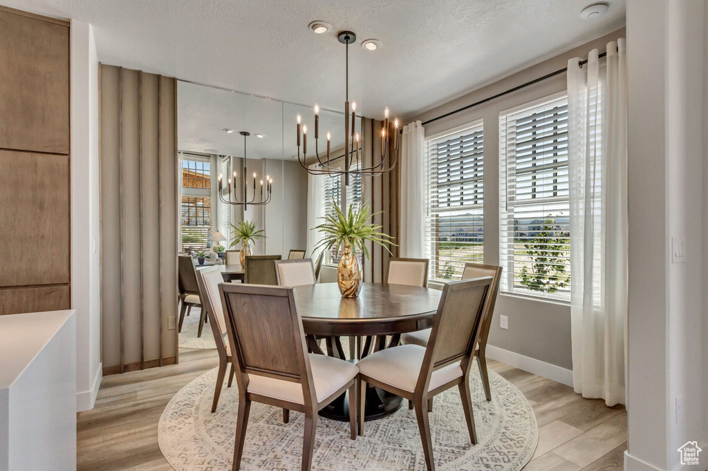 Dining space featuring an inviting chandelier, a textured ceiling, and light hardwood / wood-style flooring