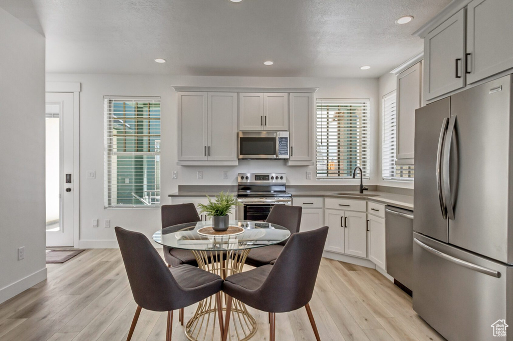 Kitchen featuring stainless steel appliances, light hardwood / wood-style flooring, white cabinetry, and sink