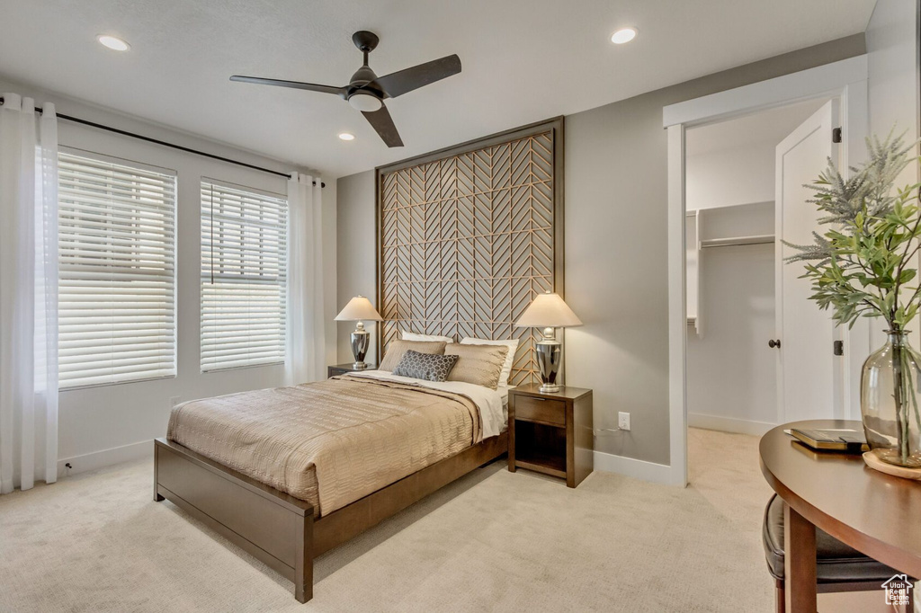Carpeted bedroom with a walk in closet and ceiling fan