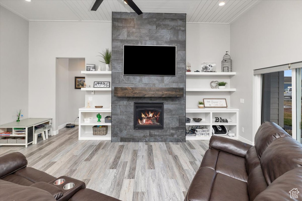 Living room featuring a tiled fireplace, wood ceiling, ceiling fan, and light hardwood / wood-style flooring