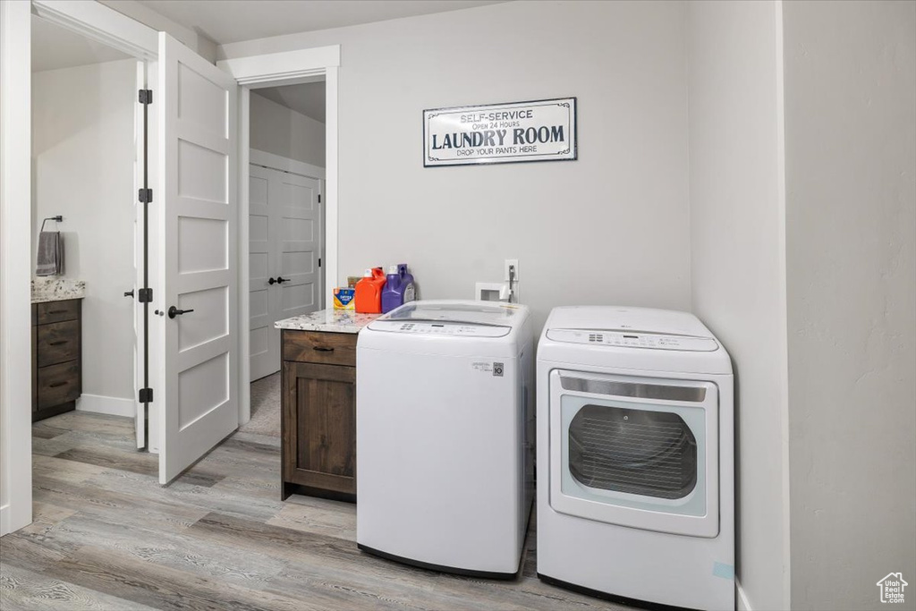 Laundry room with cabinets, separate washer and dryer, and light hardwood / wood-style flooring