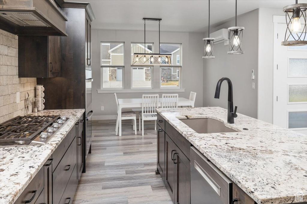 Kitchen with a healthy amount of sunlight, premium range hood, decorative light fixtures, and light wood-type flooring