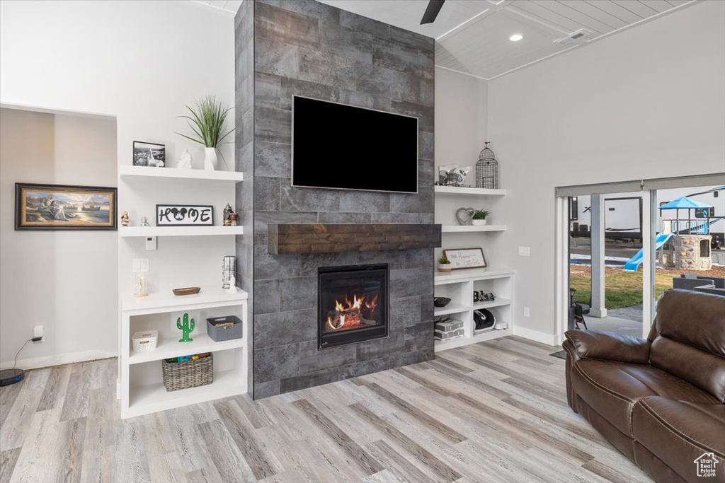 Living room with tile walls, a tile fireplace, and light hardwood / wood-style flooring
