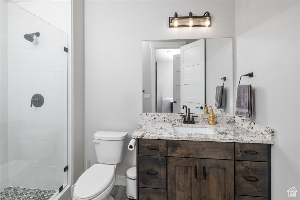 Bathroom with vanity, a tile shower, and toilet