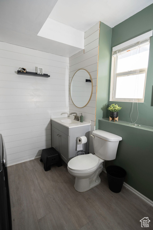 Bathroom featuring toilet, wood walls, hardwood / wood-style floors, and vanity