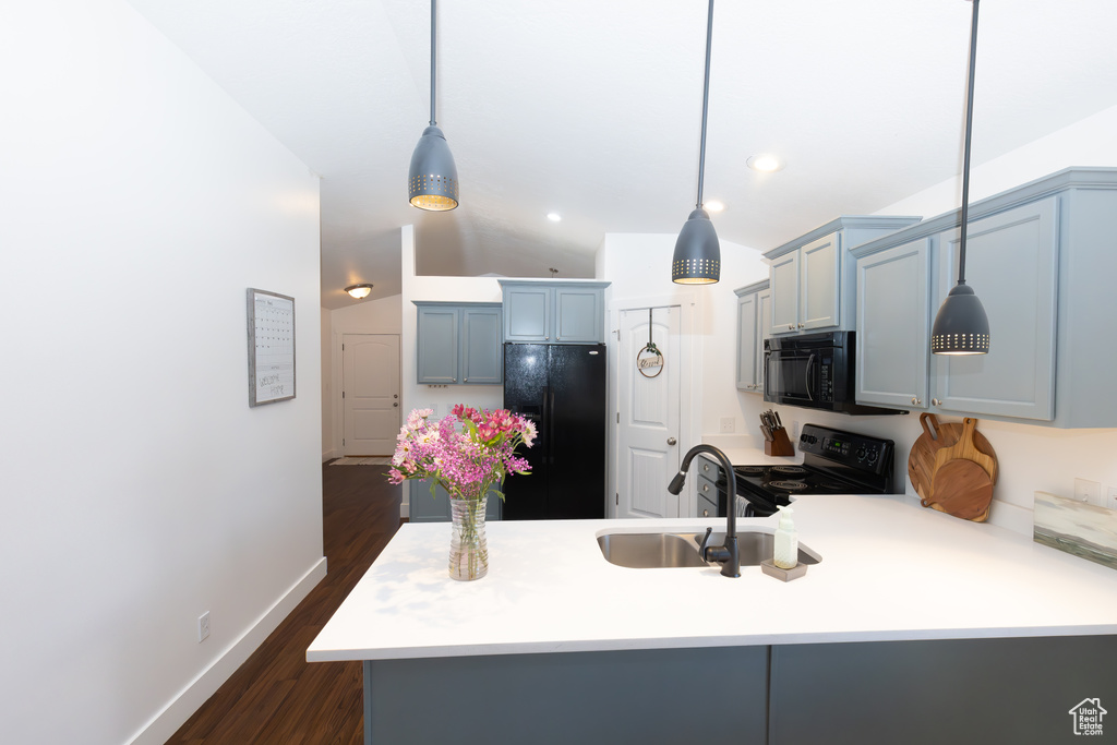Kitchen featuring dark hardwood / wood-style floors, kitchen peninsula, sink, black appliances, and decorative light fixtures
