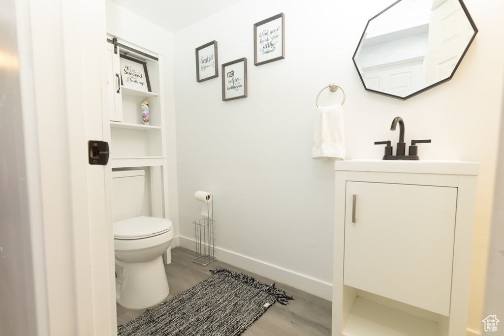 Bathroom with toilet, vanity, and wood-type flooring