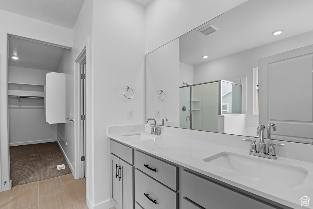 Bathroom featuring tile floors, a shower with shower door, and double sink vanity