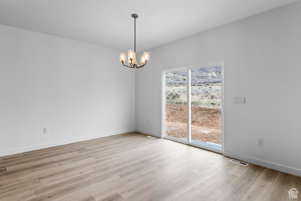Empty room featuring a chandelier and light hardwood / wood-style floors