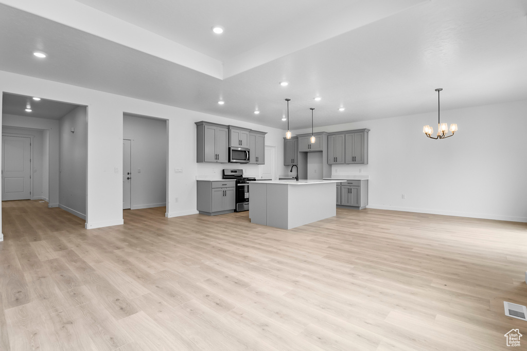 Kitchen featuring decorative light fixtures, stainless steel appliances, light hardwood / wood-style flooring, and a notable chandelier