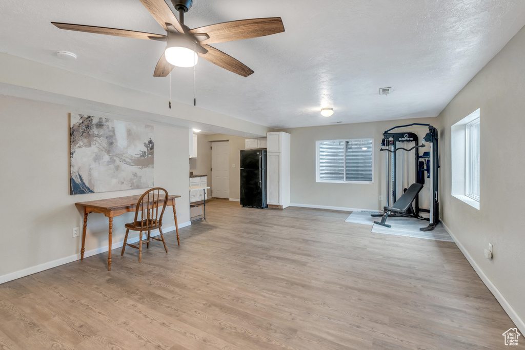 Exercise room with light hardwood / wood-style floors and ceiling fan