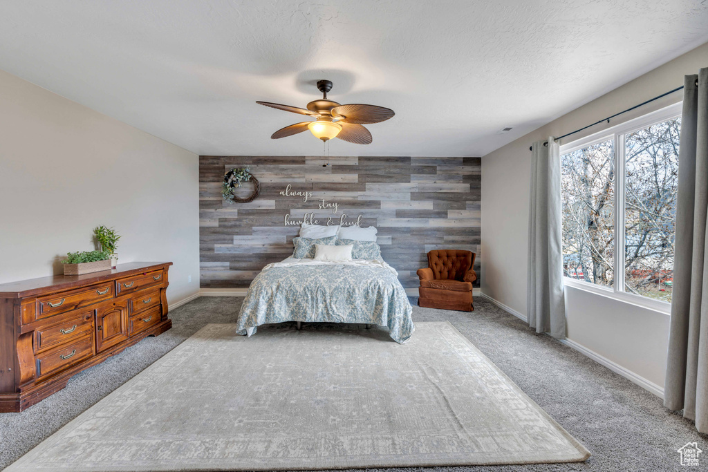Carpeted bedroom with ceiling fan and wood walls