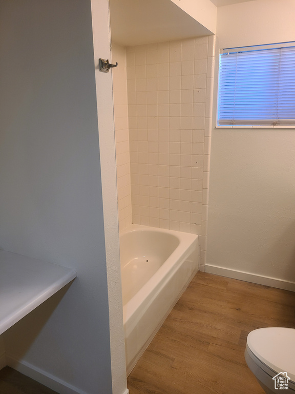 Bathroom featuring toilet, bathtub / shower combination, and wood-type flooring