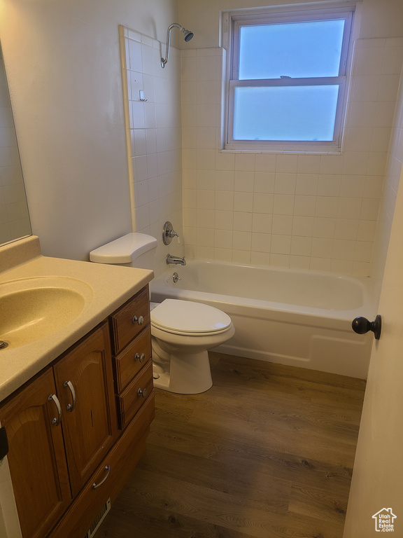 Full bathroom with vanity, toilet, tiled shower / bath, and hardwood / wood-style flooring