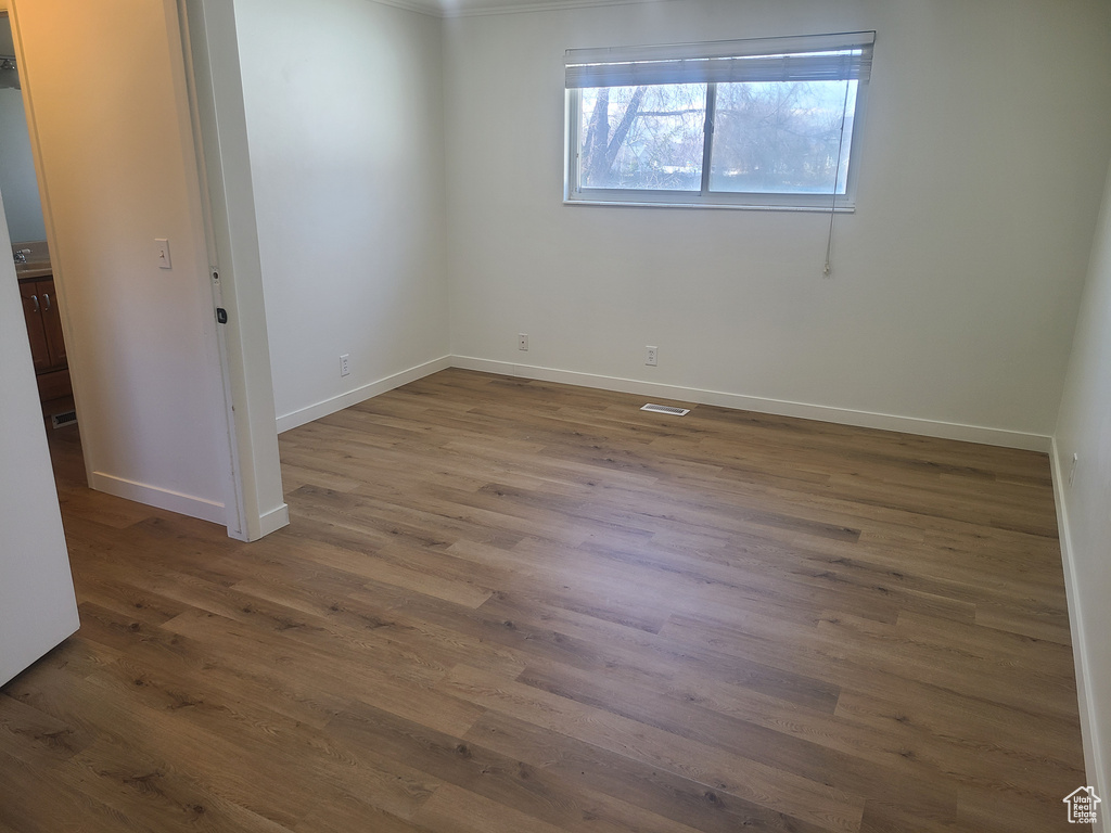 Empty room featuring dark hardwood / wood-style flooring and crown molding