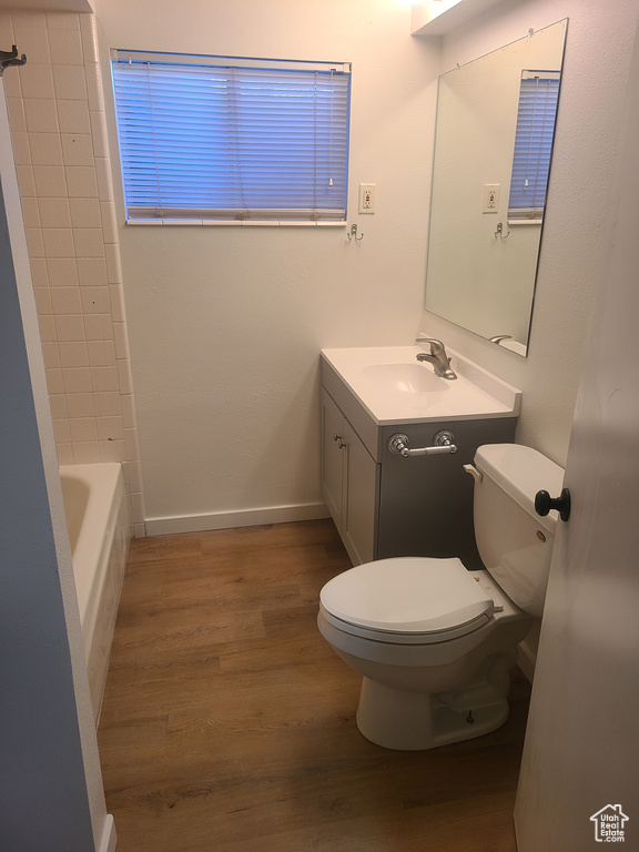 Full bathroom featuring hardwood / wood-style floors, shower / washtub combination, toilet, and oversized vanity