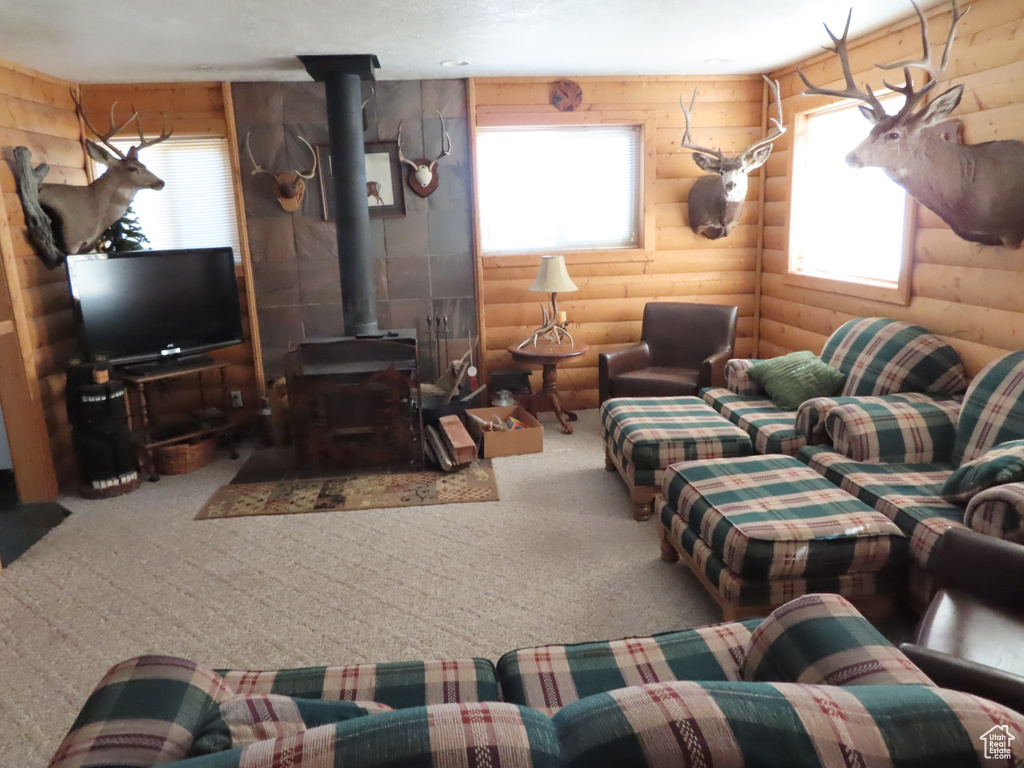 Living room featuring carpet floors, log walls, and a wood stove