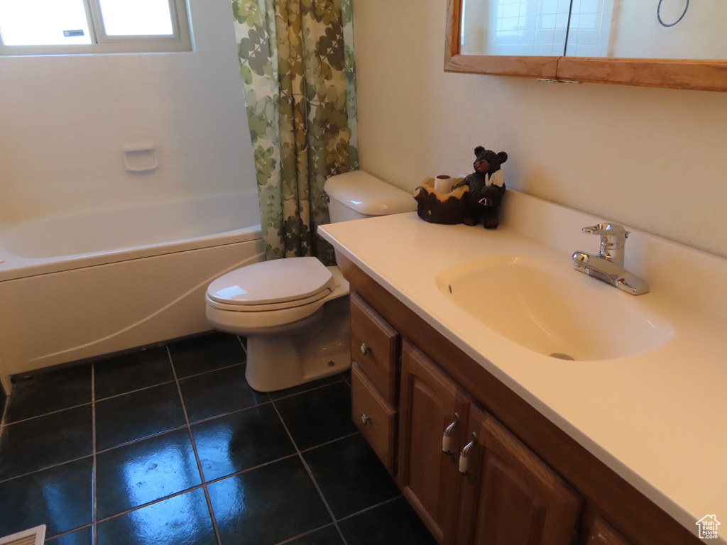 Full bathroom with toilet, large vanity, shower / tub combo, and tile flooring