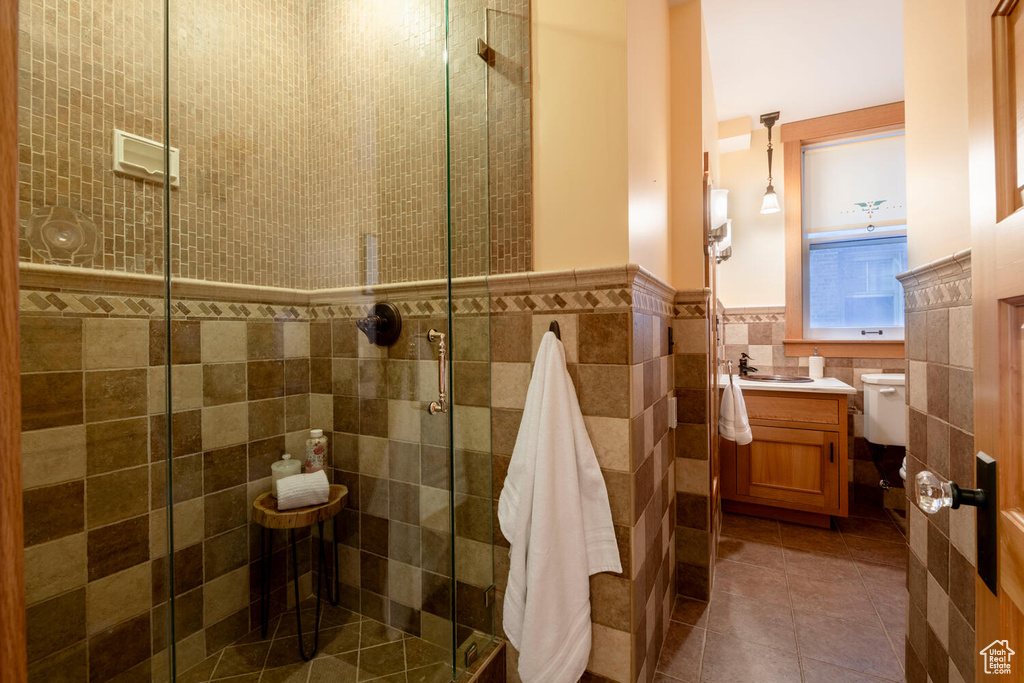Bathroom with tile floors, an enclosed shower, tile walls, and vanity