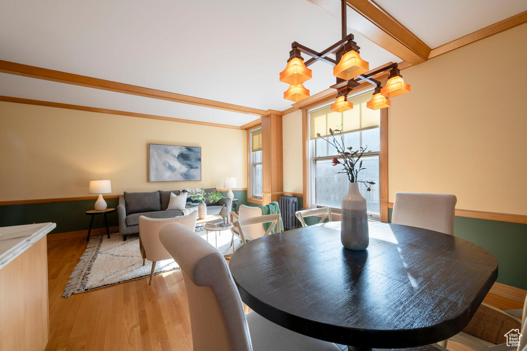 Dining room with light hardwood / wood-style flooring, an inviting chandelier, and beam ceiling
