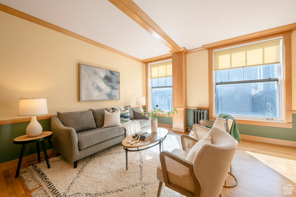 Living room with beam ceiling, radiator, and light hardwood / wood-style flooring
