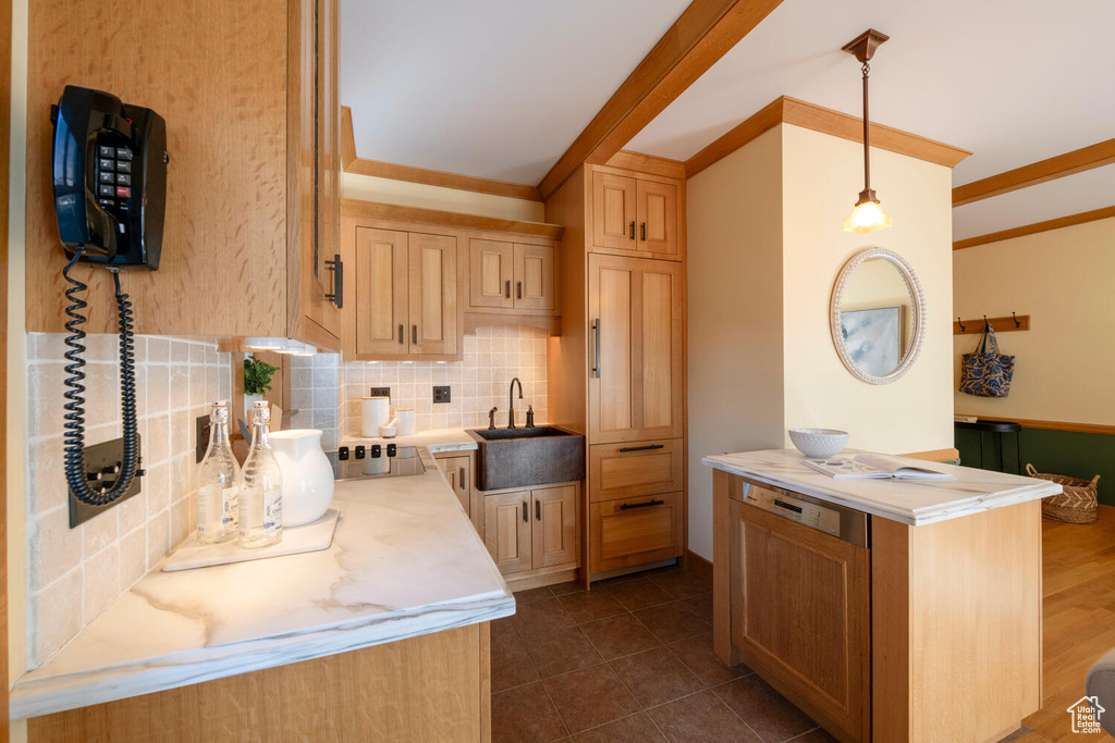 Kitchen featuring backsplash, sink, light brown cabinets, and decorative light fixtures