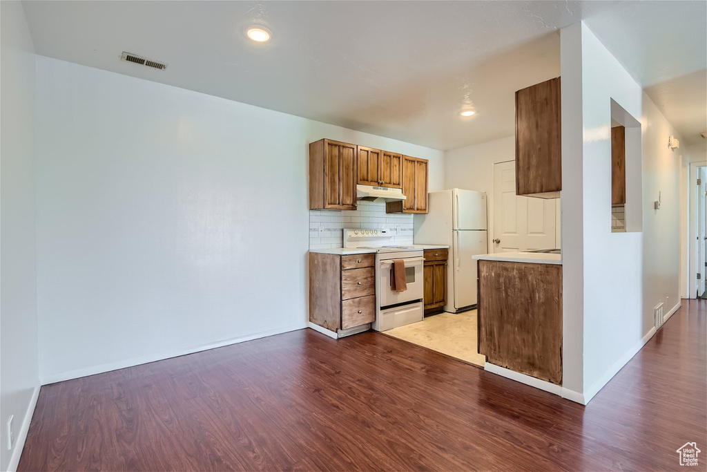 Kitchen with white appliances, tasteful backsplash, and hardwood / wood-style flooring