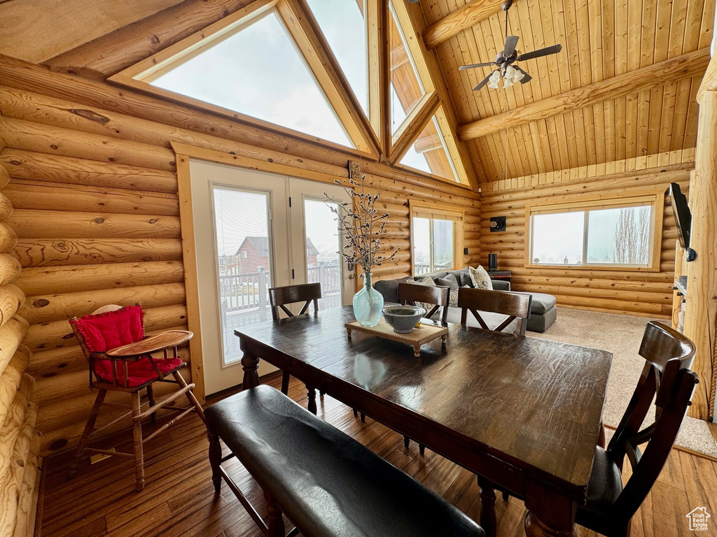 Dining area featuring ceiling fan, hardwood / wood-style floors, wood ceiling, rustic walls, and beam ceiling