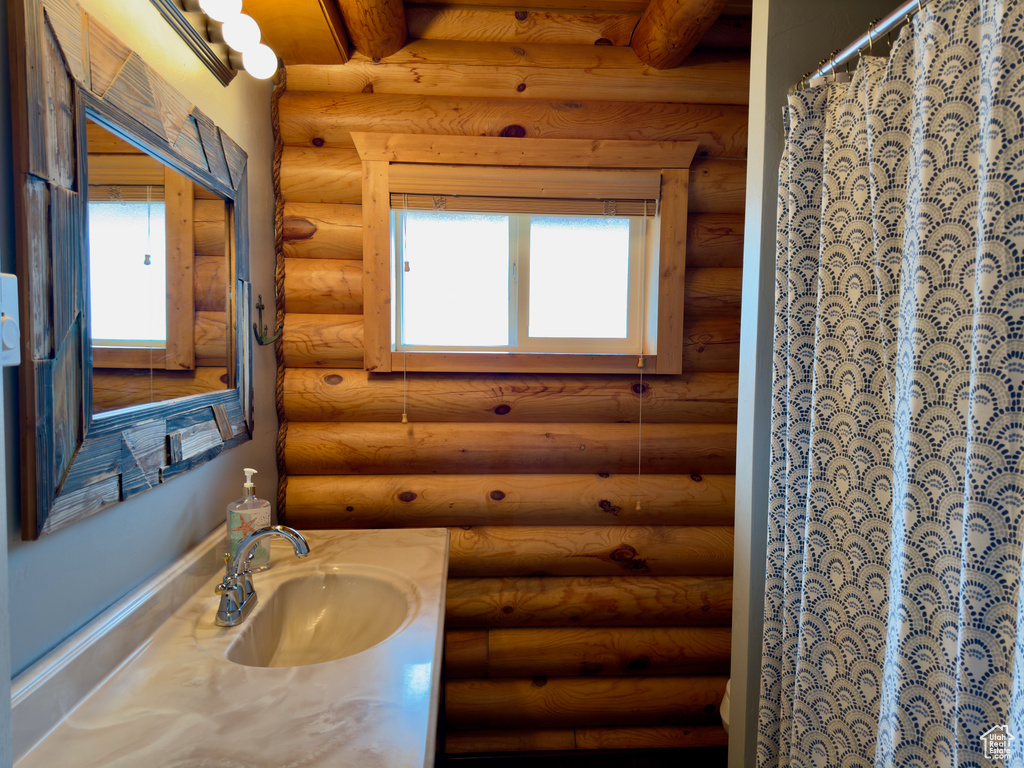 Bathroom with rustic walls, vanity with extensive cabinet space, and a healthy amount of sunlight