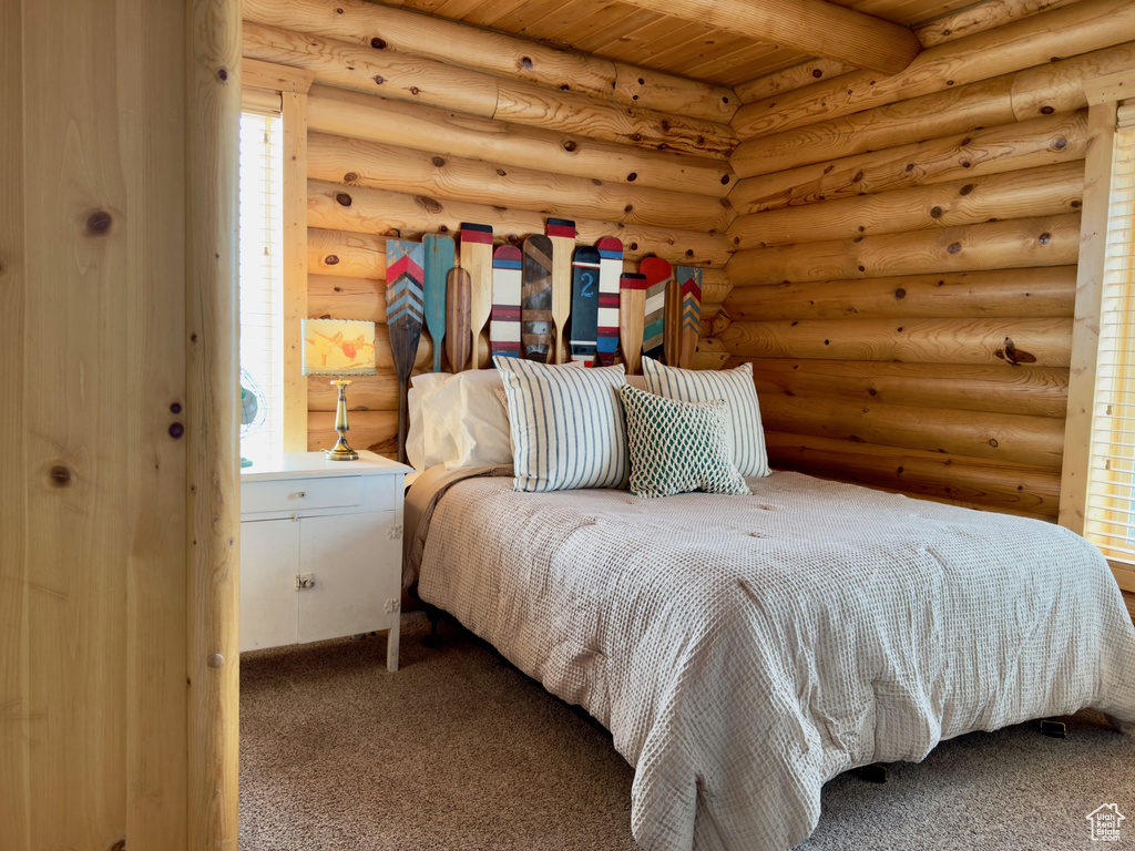 Carpeted bedroom with wood ceiling, beam ceiling, and log walls