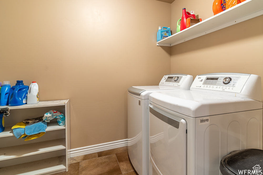 Laundry room featuring washer and clothes dryer and dark tile flooring