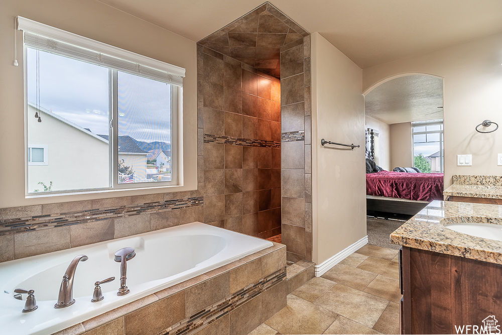 Bathroom featuring tiled tub, tile flooring, and vanity