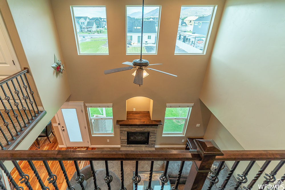Staircase with a fireplace, ceiling fan, wood-type flooring, and a high ceiling
