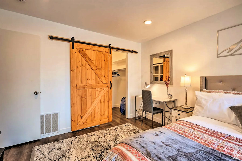 Bedroom with a barn door, a closet, and dark hardwood / wood-style floors