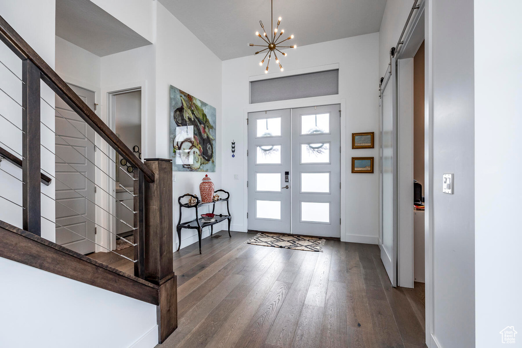 Entrance foyer featuring french doors, dark hardwood / wood-style flooring, a notable chandelier, and a barn door