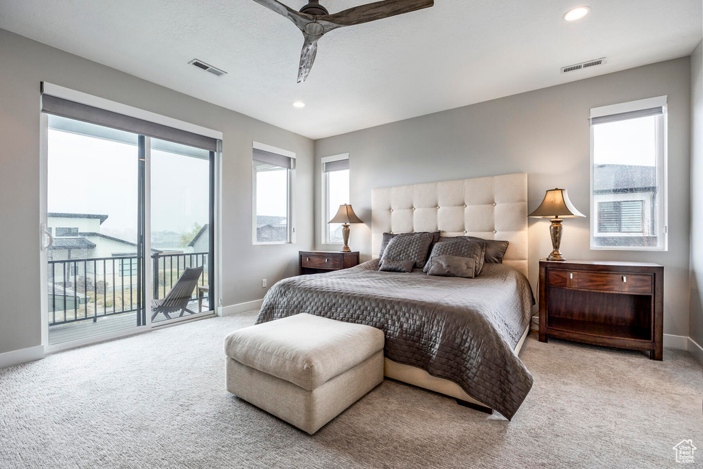 Bedroom featuring light colored carpet, multiple windows, and ceiling fan