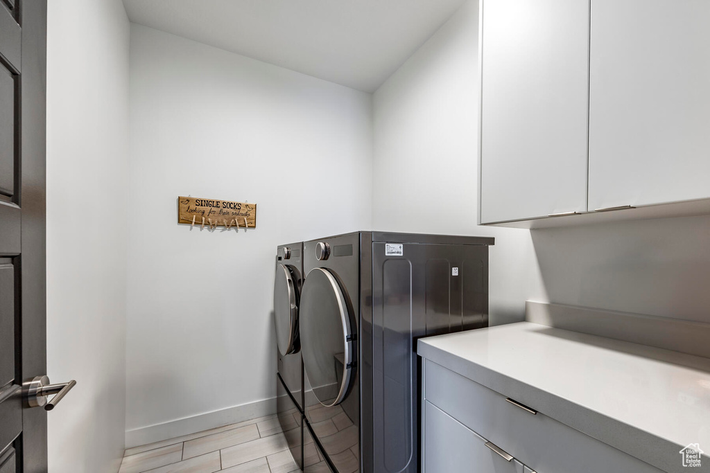 Laundry room featuring washing machine and clothes dryer and cabinets