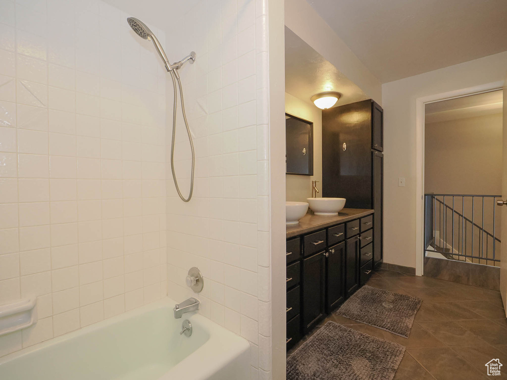 Bathroom with double sink, tile floors, vanity with extensive cabinet space, and tiled shower / bath