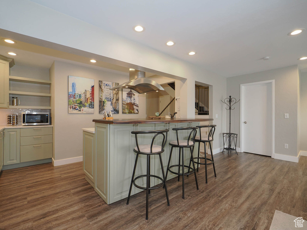 Kitchen featuring dark hardwood / wood-style floors, a kitchen breakfast bar, and island exhaust hood