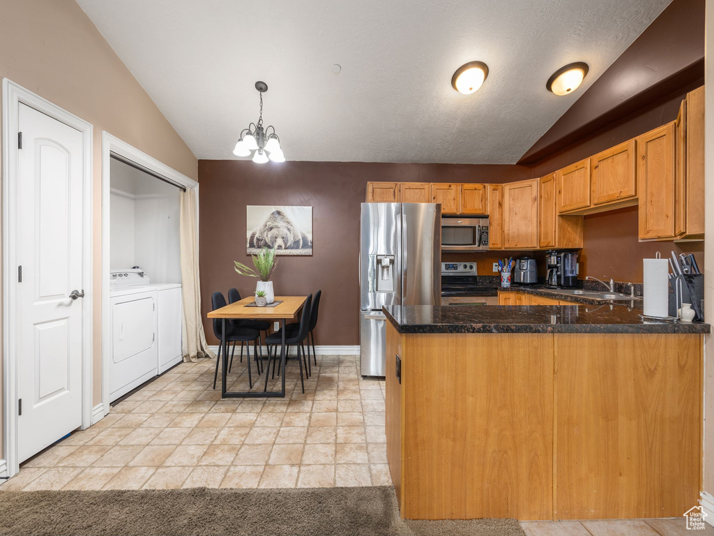 Kitchen featuring light tile flooring, a notable chandelier, stainless steel appliances, washer and clothes dryer, and pendant lighting