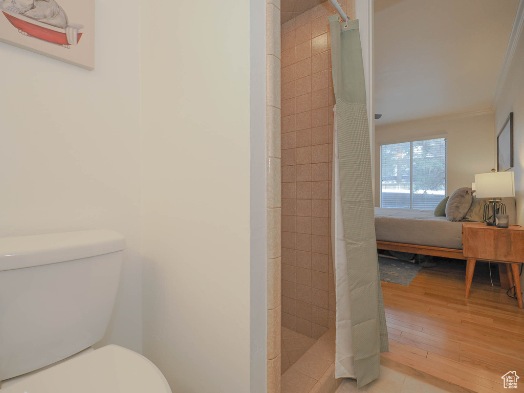 Bathroom featuring a shower with curtain, toilet, hardwood / wood-style flooring, and ornamental molding