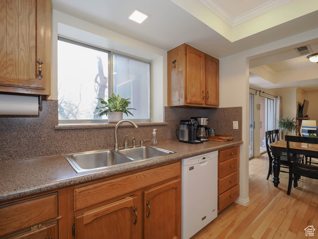 Kitchen featuring sink, a raised ceiling, white dishwasher, backsplash, and light hardwood / wood-style floors