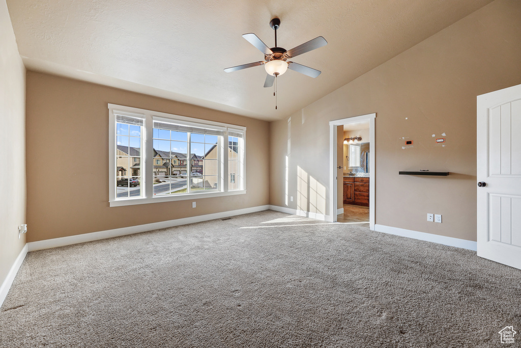 Carpeted empty room featuring ceiling fan and high vaulted ceiling