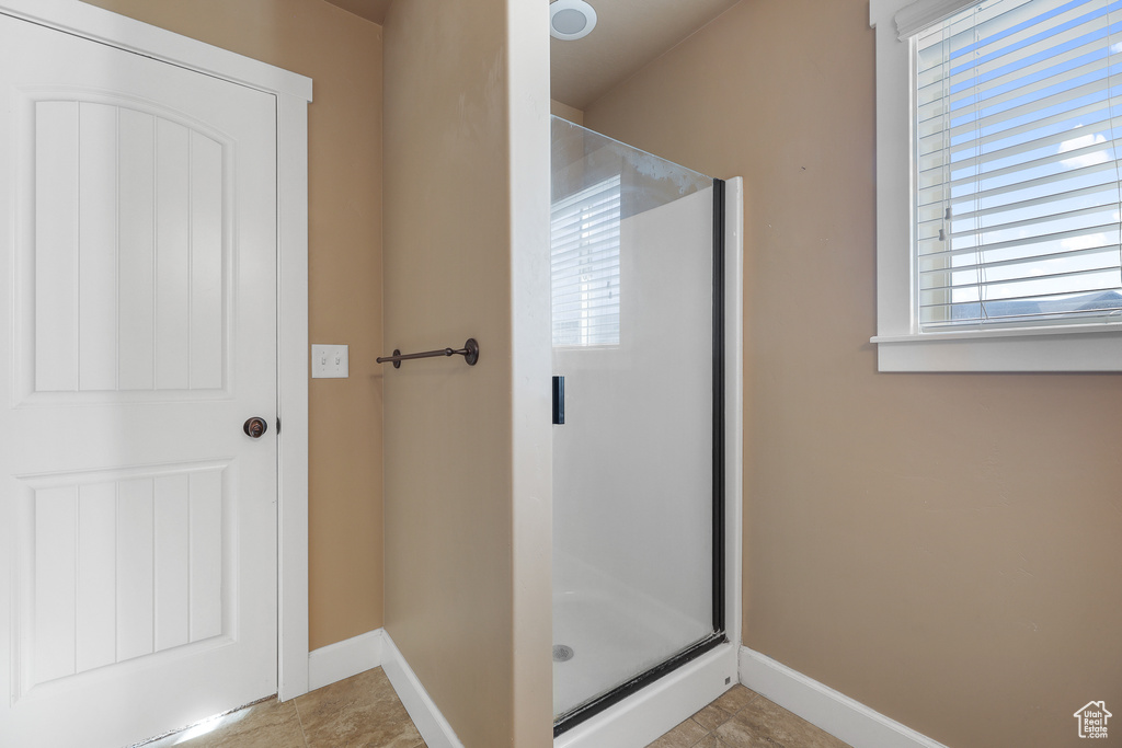 Bathroom with a shower with door and tile flooring