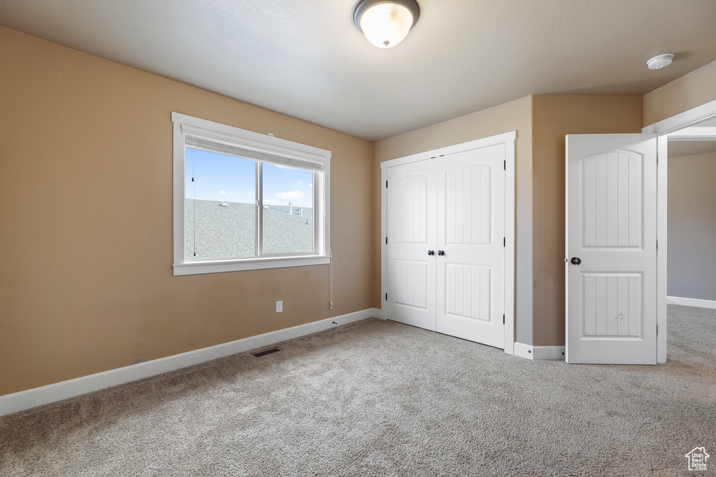 Unfurnished bedroom featuring a closet and light colored carpet
