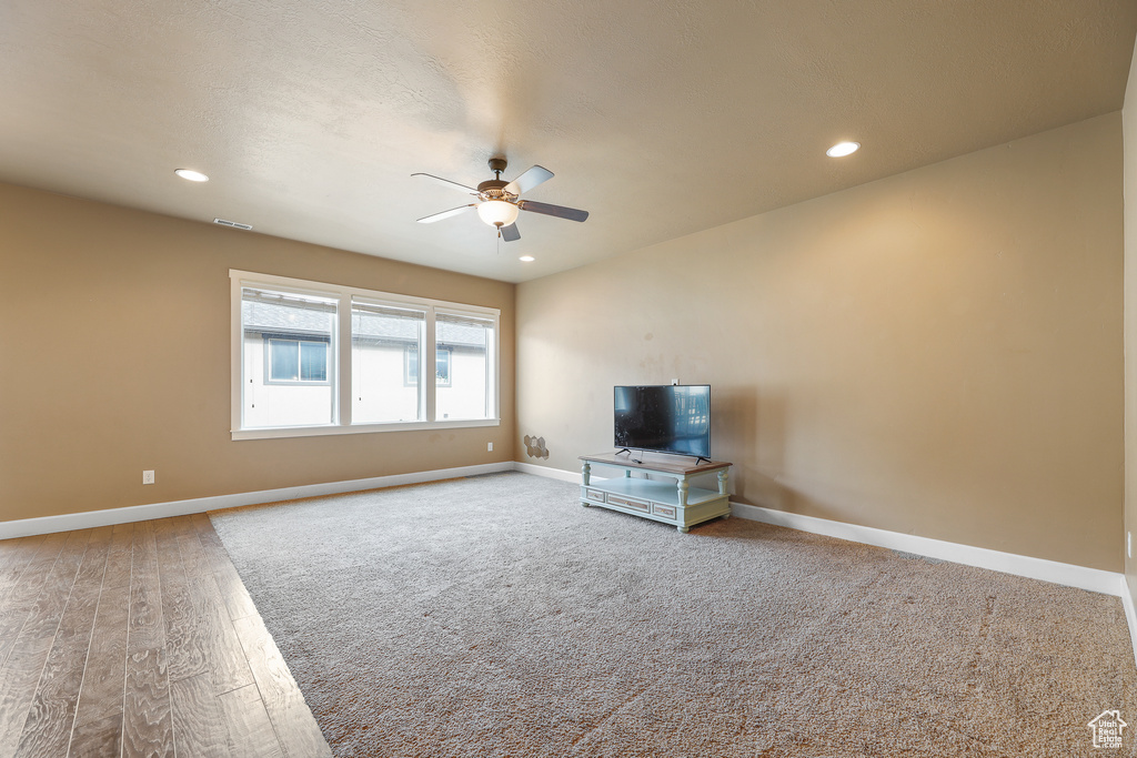 Unfurnished living room featuring light carpet and ceiling fan