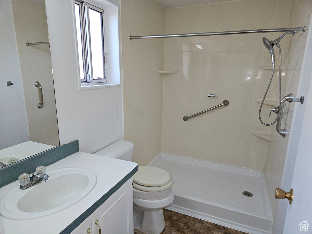 Bathroom featuring plenty of natural light, tile floors, vanity with extensive cabinet space, and toilet