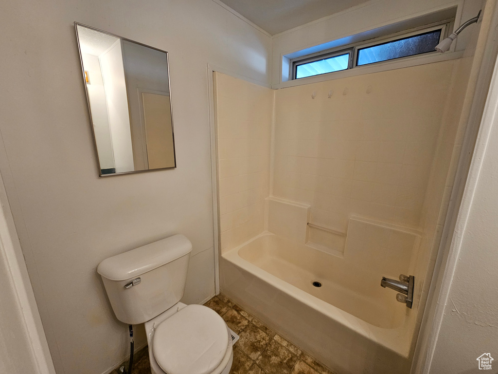 Bathroom featuring toilet, washtub / shower combination, and tile flooring