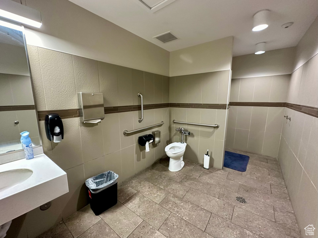 Bathroom with tile floors, toilet, and tile walls